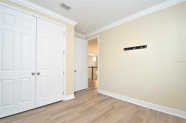 unfurnished bedroom with a closet, light hardwood / wood-style floors, and ornamental molding