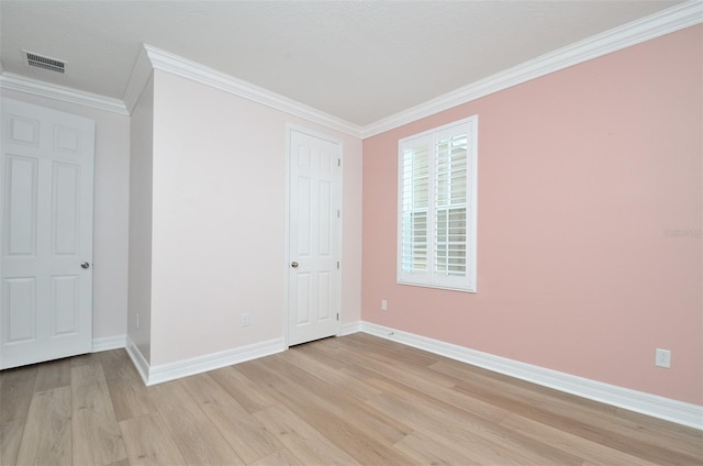 empty room with crown molding and light hardwood / wood-style floors