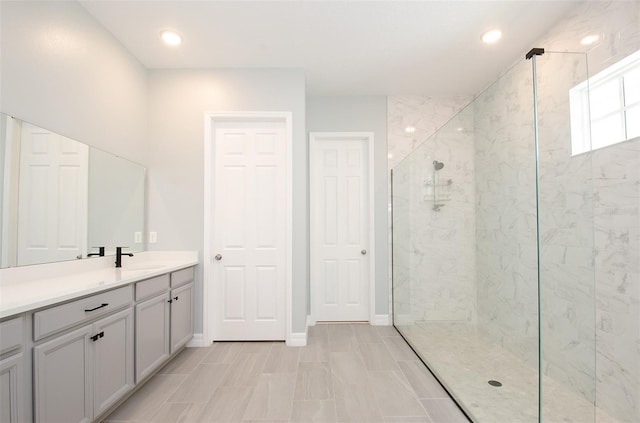 bathroom with tiled shower and vanity