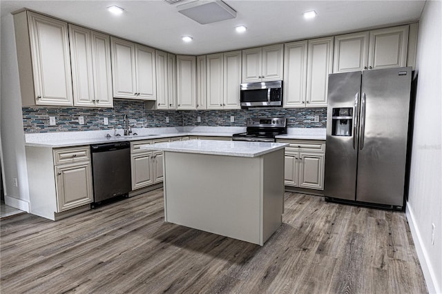 kitchen featuring backsplash, stainless steel appliances, a center island, sink, and hardwood / wood-style flooring