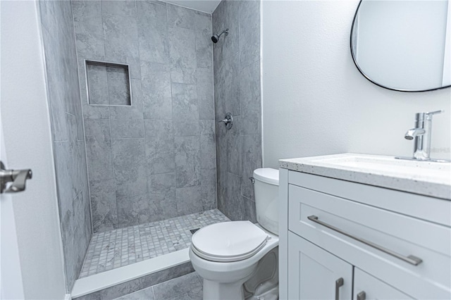 bathroom featuring tiled shower, vanity, toilet, and tile patterned floors