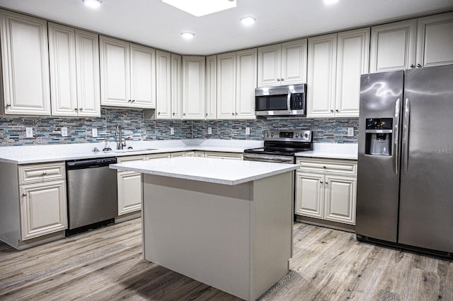 kitchen featuring stainless steel appliances, a center island, decorative backsplash, sink, and light hardwood / wood-style floors