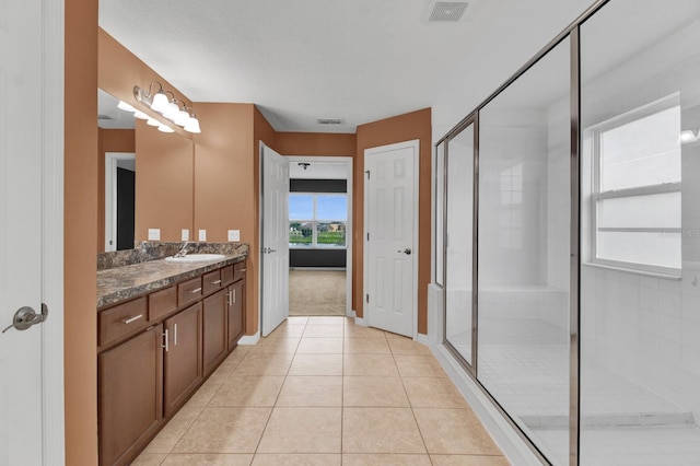 bathroom featuring vanity, a shower with shower door, and tile patterned flooring