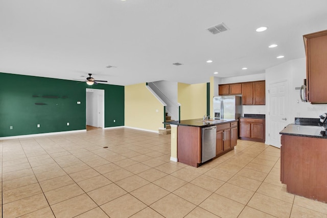 kitchen featuring appliances with stainless steel finishes, light tile patterned flooring, sink, ceiling fan, and a kitchen island with sink