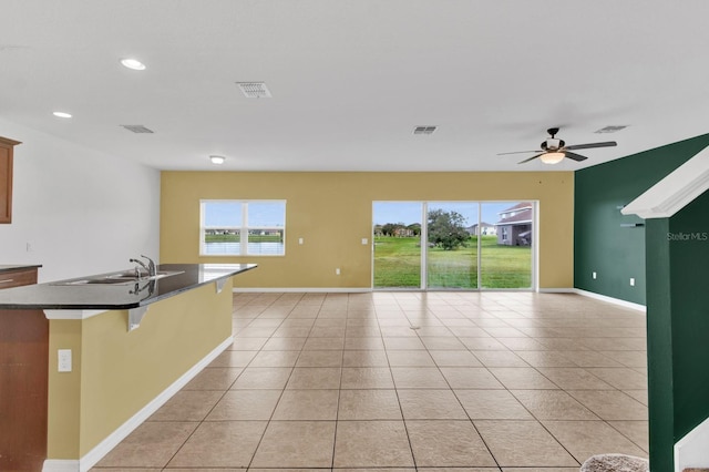 kitchen featuring sink, an island with sink, a kitchen breakfast bar, ceiling fan, and light tile patterned floors