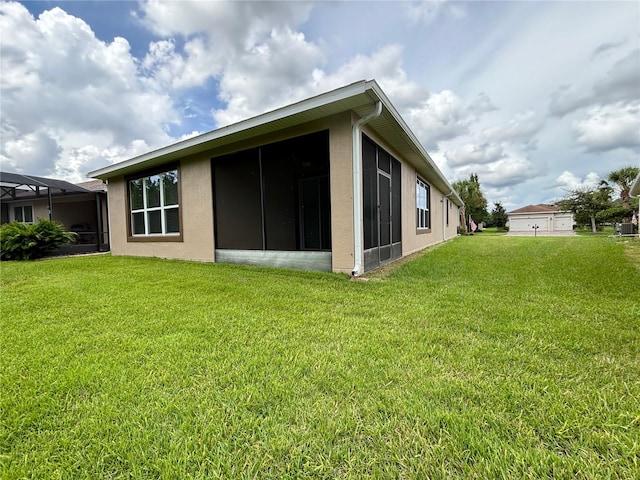 rear view of house featuring a yard and a sunroom