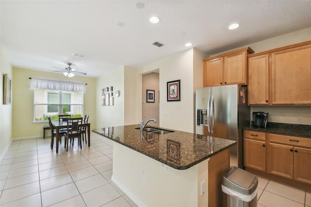 kitchen with light tile patterned floors, sink, an island with sink, stainless steel refrigerator with ice dispenser, and ceiling fan