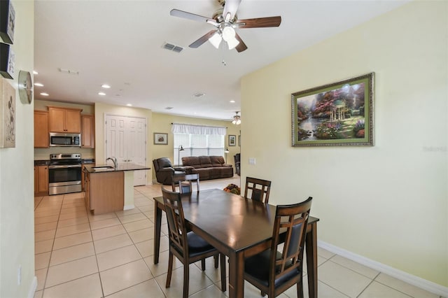 dining space with ceiling fan, light tile patterned floors, and sink