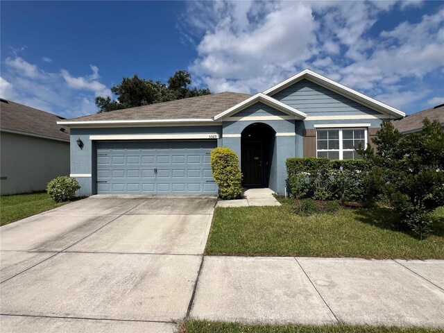 single story home with driveway, stucco siding, an attached garage, and a front yard