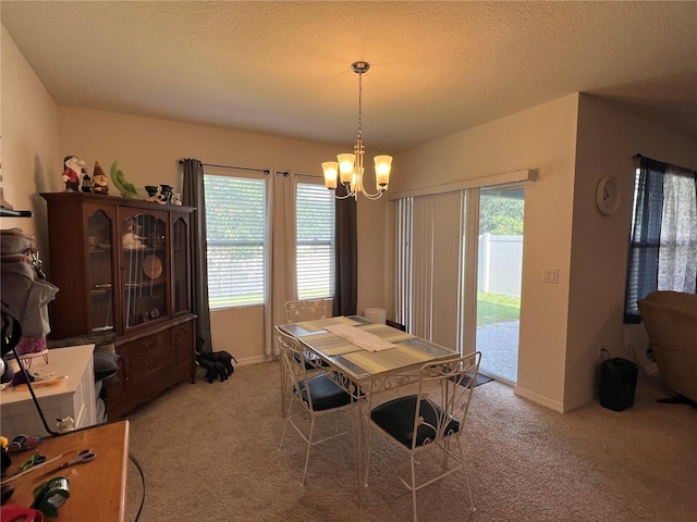 dining room with light colored carpet, a textured ceiling, baseboards, and an inviting chandelier