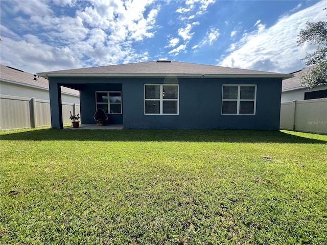 back of property with a fenced backyard, a lawn, and stucco siding