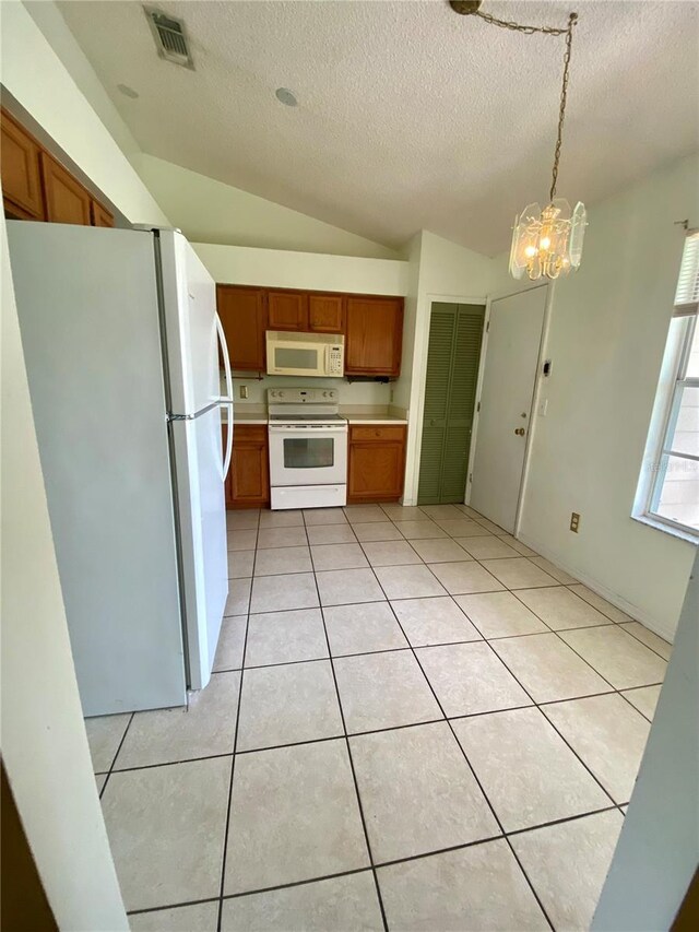 kitchen featuring a chandelier, light tile patterned floors, a textured ceiling, lofted ceiling, and white appliances