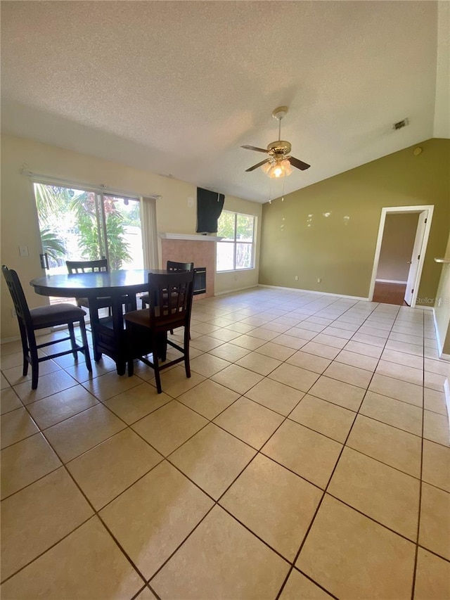 tiled dining space featuring ceiling fan, lofted ceiling, and a textured ceiling