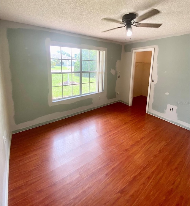 spare room with ceiling fan, wood-type flooring, and a textured ceiling