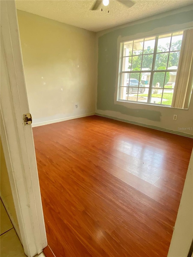 empty room with ceiling fan, light hardwood / wood-style floors, and a textured ceiling