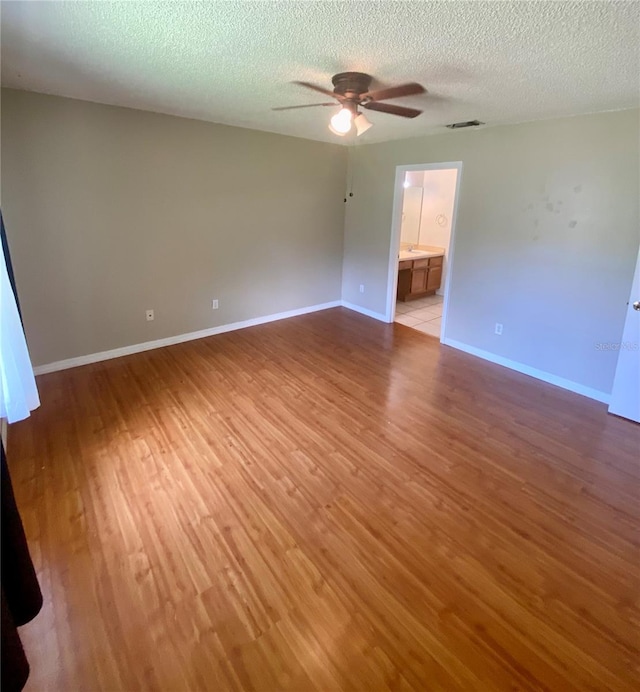 spare room with ceiling fan, wood-type flooring, and a textured ceiling