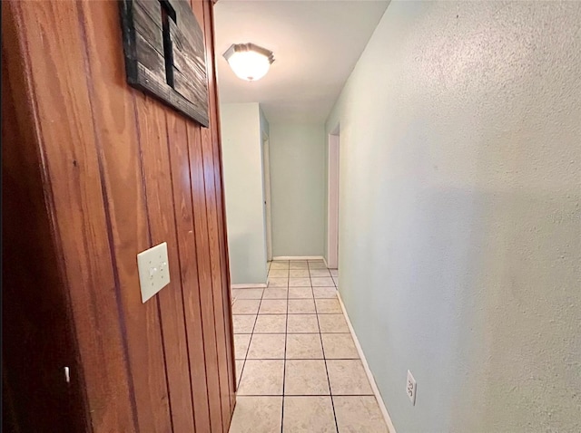 corridor featuring wood walls and light tile patterned floors