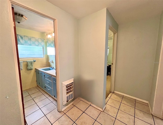 bathroom with tile patterned flooring, heating unit, tile walls, and vanity