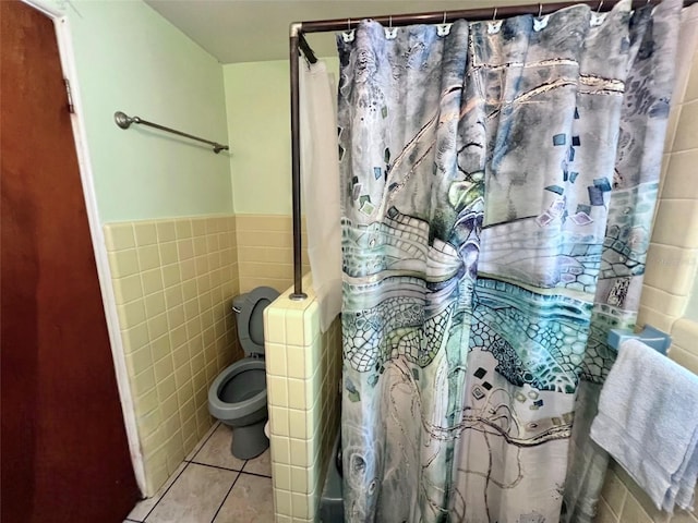 full bath featuring tile patterned flooring, wainscoting, curtained shower, tile walls, and toilet