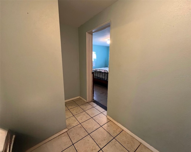 hallway featuring light tile patterned flooring and baseboards