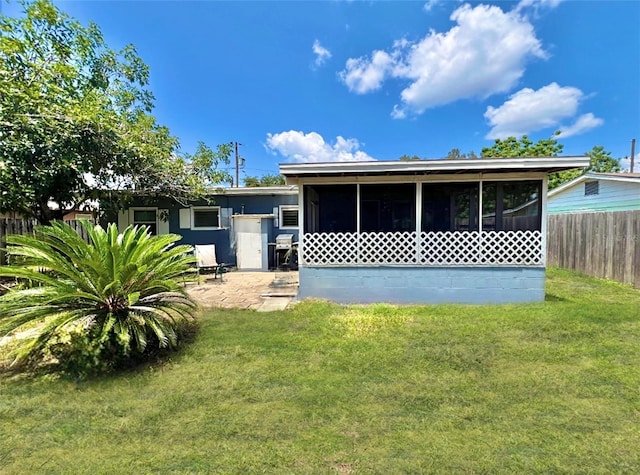 rear view of house featuring a sunroom and a yard