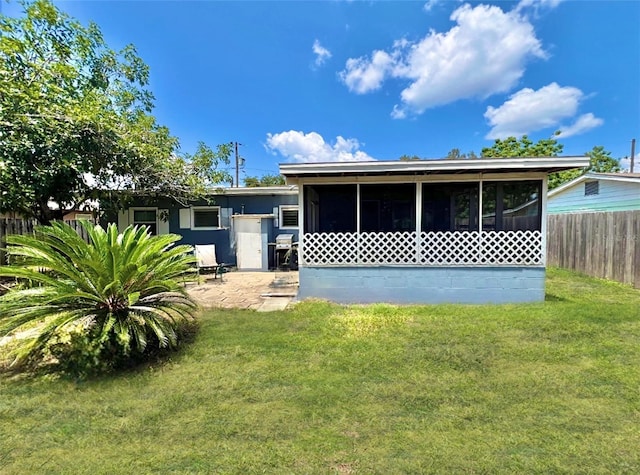 view of front of property with a front lawn, fence, a sunroom, and a patio