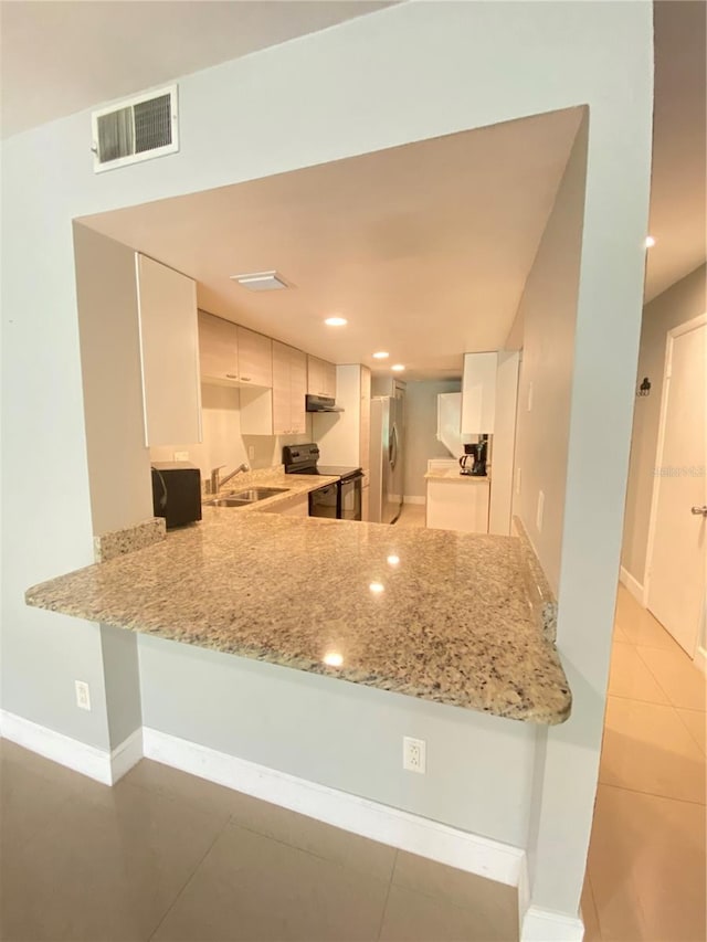 kitchen with range with electric stovetop, stainless steel fridge, white cabinets, and sink