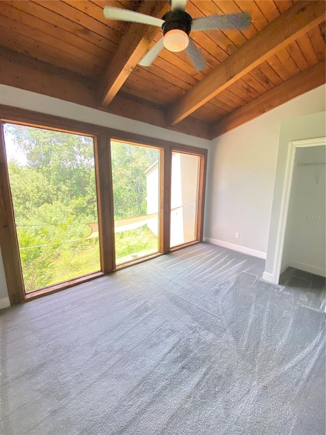 carpeted empty room with beamed ceiling, wood ceiling, ceiling fan, and a healthy amount of sunlight