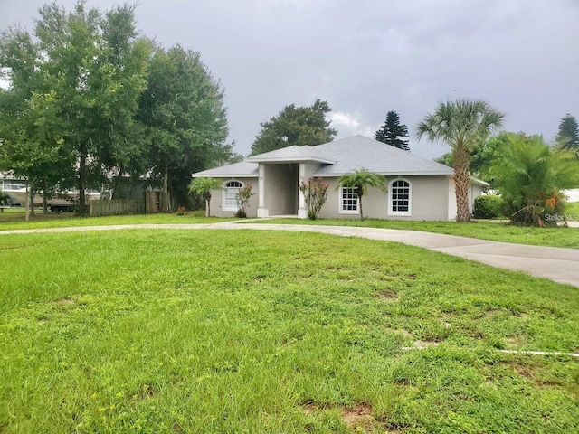 view of front of property featuring concrete driveway, a front lawn, and stucco siding