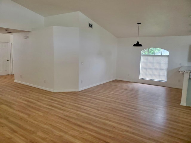 unfurnished room with vaulted ceiling, light wood-type flooring, visible vents, and baseboards