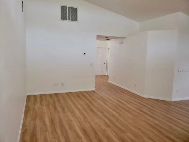 unfurnished room featuring vaulted ceiling and light hardwood / wood-style floors