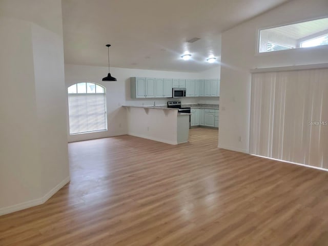 kitchen with decorative light fixtures, stainless steel appliances, light countertops, open floor plan, and a peninsula