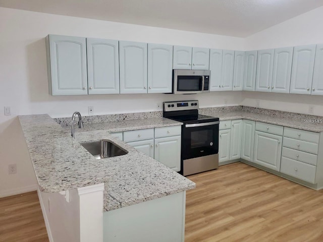 kitchen with sink, stainless steel appliances, kitchen peninsula, and light wood-type flooring