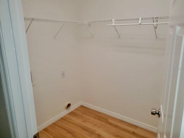 clothes washing area featuring electric dryer hookup, baseboards, and wood finished floors