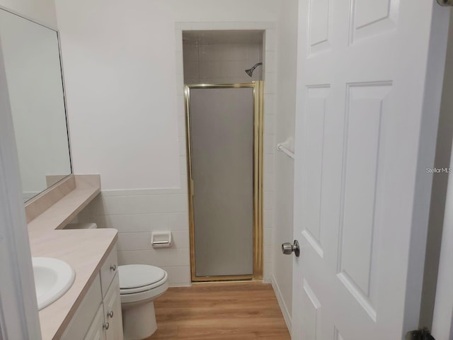 bathroom featuring hardwood / wood-style flooring, a shower with shower door, vanity, and toilet