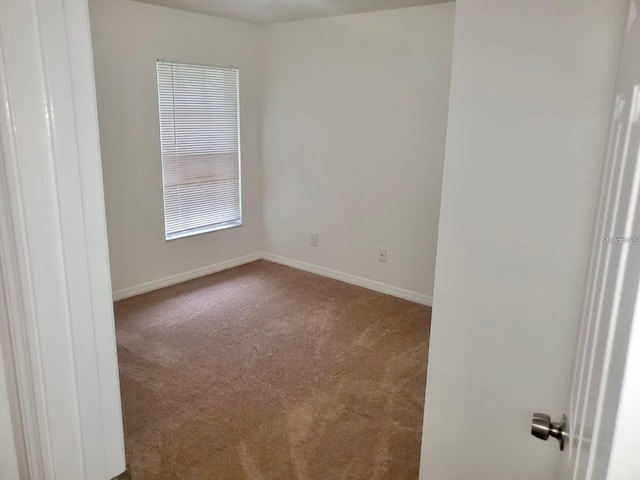 carpeted empty room featuring baseboards