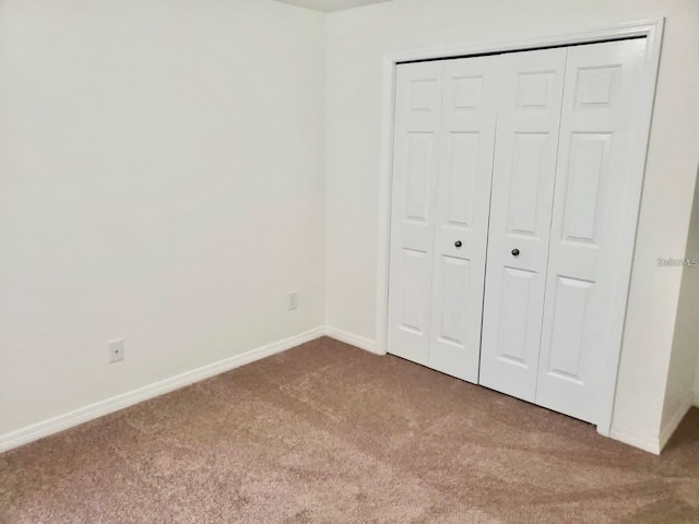 unfurnished bedroom featuring carpet, a closet, and baseboards