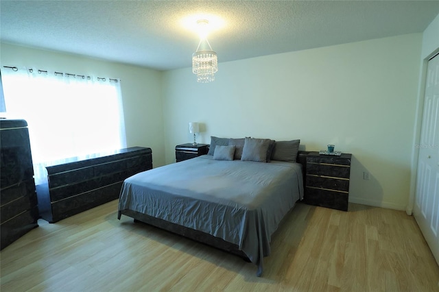 bedroom with a closet, hardwood / wood-style flooring, an inviting chandelier, and a textured ceiling