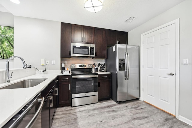 kitchen with light wood-type flooring, dark brown cabinetry, sink, and stainless steel appliances