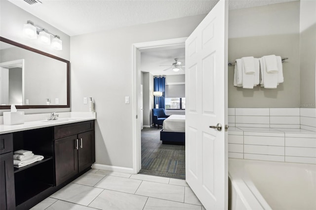 bathroom featuring a textured ceiling, tile patterned flooring, vanity, ceiling fan, and a bathtub