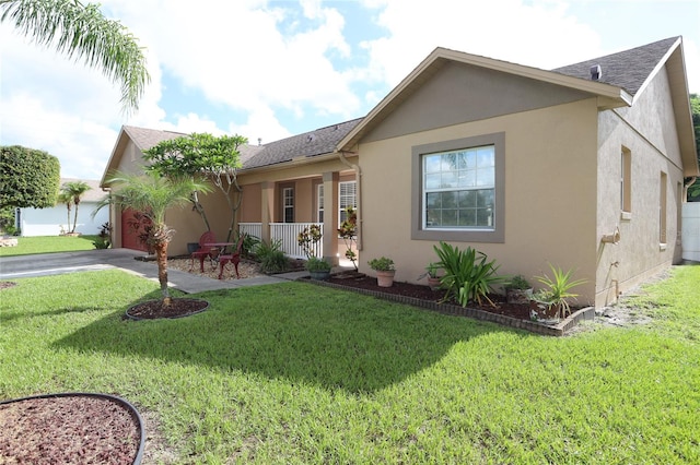 ranch-style home featuring a garage, covered porch, and a front yard