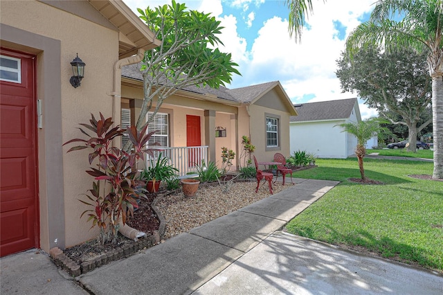 view of exterior entry featuring a porch and a yard