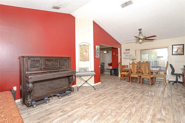 interior space featuring a textured ceiling, vaulted ceiling, light hardwood / wood-style flooring, and ceiling fan