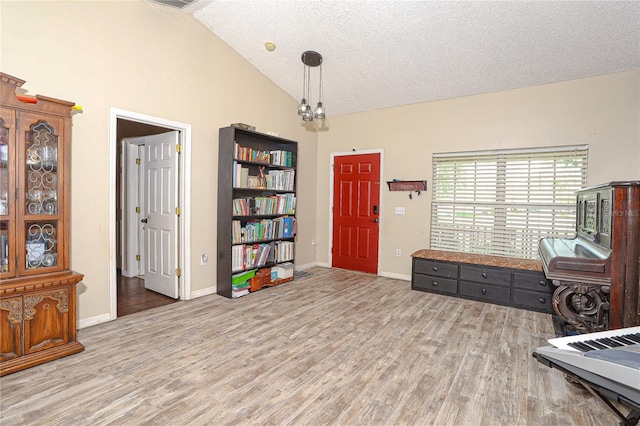 sitting room with a textured ceiling, an inviting chandelier, vaulted ceiling, and light wood-type flooring