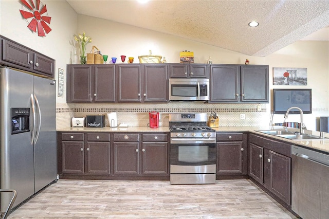 kitchen featuring dark brown cabinetry, sink, backsplash, lofted ceiling, and appliances with stainless steel finishes