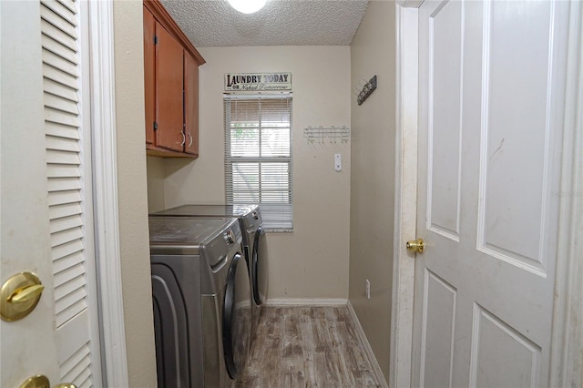 laundry room with separate washer and dryer, cabinets, a textured ceiling, and light wood-type flooring