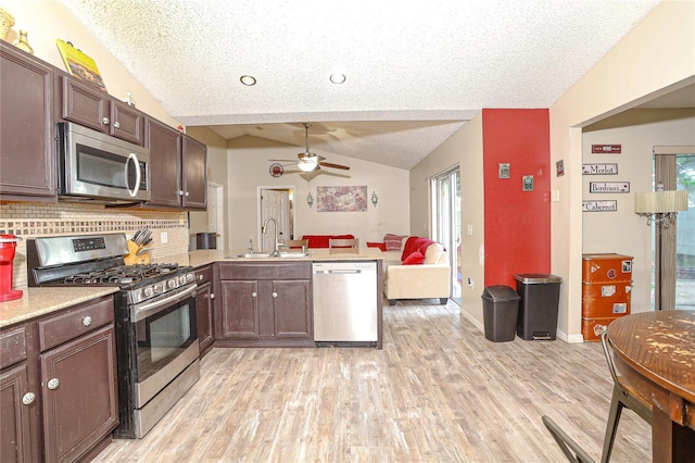 kitchen featuring lofted ceiling, backsplash, sink, kitchen peninsula, and stainless steel appliances