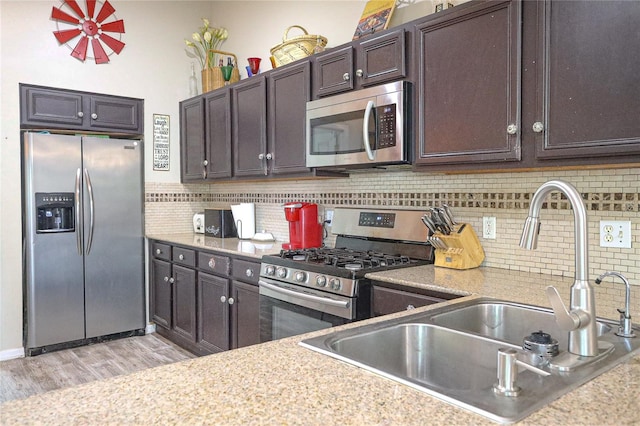 kitchen featuring sink, stainless steel appliances, decorative backsplash, dark brown cabinets, and light wood-type flooring