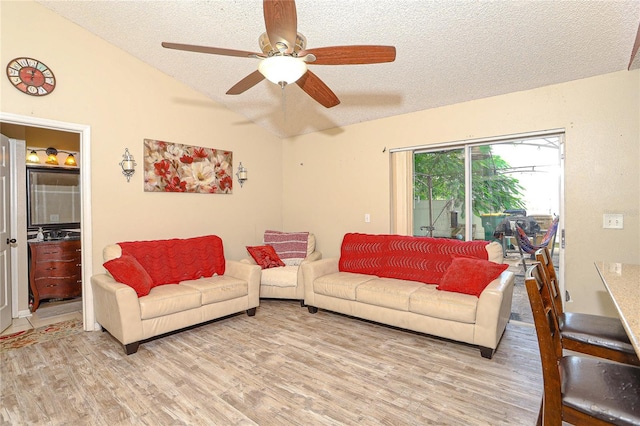 living room featuring vaulted ceiling, ceiling fan, light hardwood / wood-style flooring, and a textured ceiling