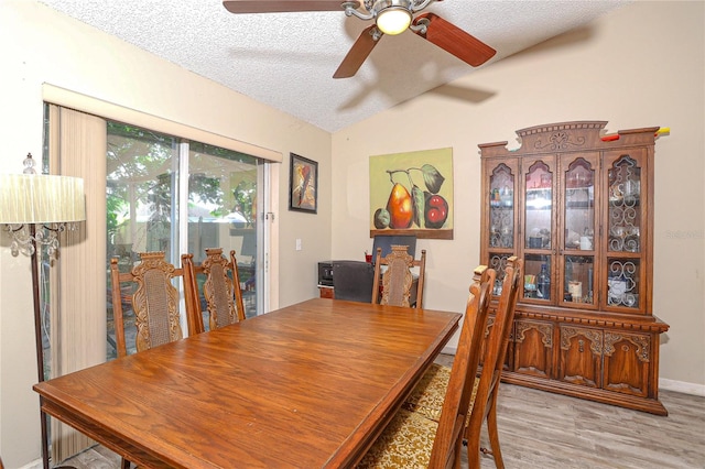 dining room featuring lofted ceiling, light hardwood / wood-style flooring, ceiling fan, and a textured ceiling